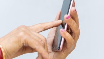 vertical-shot-wrinkled-hands-female-using-modern-smartphone_181624-44401